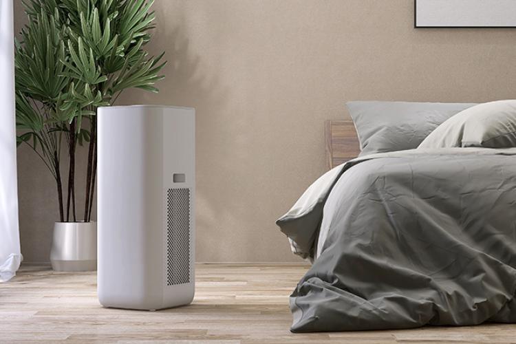 Air purifier beside a bedroom with a houseplant in the background.