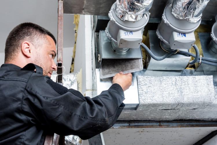 HVAC technician checking the ventilation in a HVAC unit.
